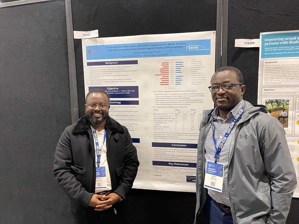 Lab members beside their poster on social protection, water access and women’s empowerment in WASH
